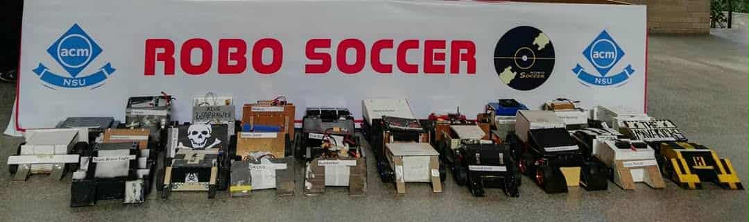 Soccer robots lined up beneath a Robo Soccer banner